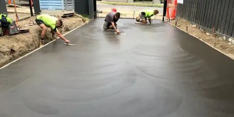 Concrete driveway cost installation in progress with fresh concrete being smoothed.
