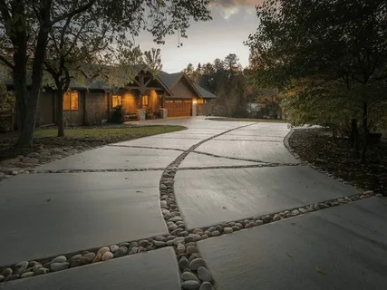 Concrete driveway cost example shown with stone-paved path to woodland home at dusk.